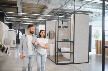 Modern bir sergi salonunu keşfeden genç bir çift, yeni fayanslar ve banyo tasarımları seçiyorlar.