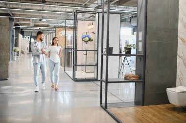 Çift modern bir galeride ev yenileme projesi için yeni banyo ve kiremit tasarımları seçiyor.