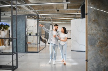 Bir sergi salonundan yeni seramik fayanslar seçen çift, ev yenileme ve iç tasarım projeleri planlıyor