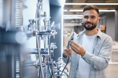 Genç adam yeni duş eşyaları alıyor, modern bir donanım ve ev dekorasyonu mağazasında ürünleri inceliyor.