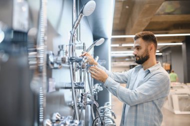 Yeni duş sistemleri ve banyo tesisatı almak için hırdavatçıya ya ya da ev geliştirme merkezine giden bir adam.