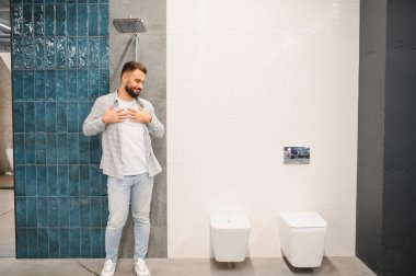 Modern bir banyoda duran mutlu adam evi için yeni bir banyo ve tuvalet tasarımı hayal ediyor.