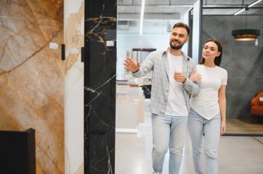 Genç çift yenileme malzemeleri için alışveriş yapıyor, yeni evleri için seramik fayanslar seçiyor veya tadilat projelerini düzenliyor.