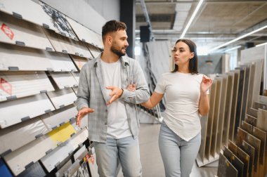 Genç çift inşaat malzemeleri için alışveriş yapıyor, yeni ev geliştirme projelerini bir mağazada tartışıyorlar.