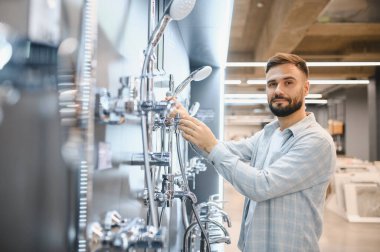 Hırdavatçı dükkanında yeni tesisat malzemeleri ve duş sistemleri satın alan bir adam hayalindeki banyoyu yaratıyor.