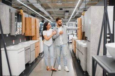 Genç bir çift yeni banyo dolaplarını ve lavaboları seçiyor ve bir galeride tadilat yapmayı planlıyor.