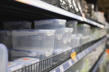Plastic containers for food storage organized on a shelf in a supermarket. Perfect for kitchenware and household goods concepts