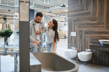 Modern banyo hijyenik malzemelerini sergide keşfeden genç bir çift, ev geliştirme projesi planlıyorlar.
