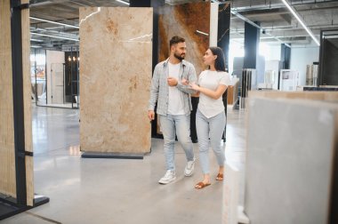 Genç bir çift, modern bir inşaat malzemeleri dükkanında yenilemek için malzeme seçiyor.