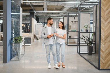Genç bir çift yeni banyo tasarımları için fayans seçeneklerini gözden geçiriyorlar.