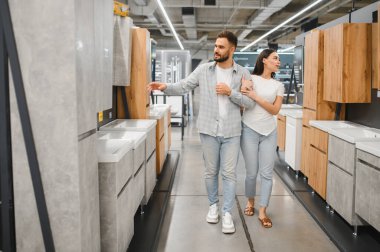 Yeni banyo mobilyalarını ve lavabolarını seçen genç çift, ev yenileme projeleri için seçeneklere bakıyor.