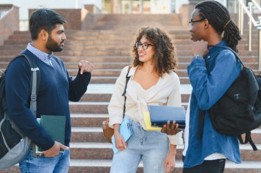 Üniversite kampüsünün merdivenlerinde sohbet eden, arkadaşlığı teşvik eden ve eğitimi tartışan bir grup genç öğrenci.