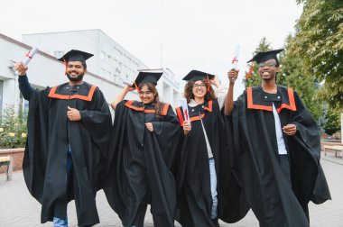 Farklı geçmişlerden gelen mutlu genç mezunlar akademik başarıyı ve kampüsteki başarıyı kutluyorlar.