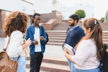 Group of young adult students from different ethnic backgrounds studying and talking on university campus