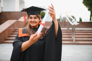 Indian university graduate woman proudly displaying her diploma, celebrating academic success and a achieving a milestone