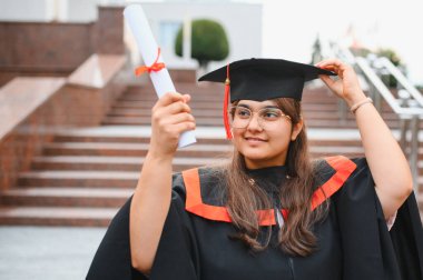 Indian university graduate woman proudly holding her diploma, celebrating educational success and achievement