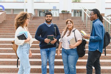 Diverse group of college students standing on university steps, holding books and backpacks, discussing before class