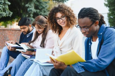 Group of diverse university students sitting outside, reading books and learning. Representing education, friendship, and collaborative study