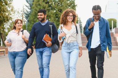 Group of diverse university students walking and smiling on campus, carrying books and backpacks, representing education and friendship