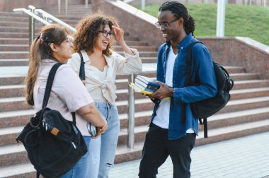 Diverse university students engaging in conversation and laughing together on campus, representing friendship and education abroad