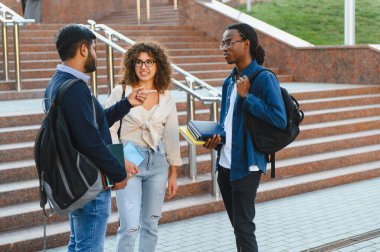 Group of diverse university students talking and interacting on campus steps, discussing studies and future careers