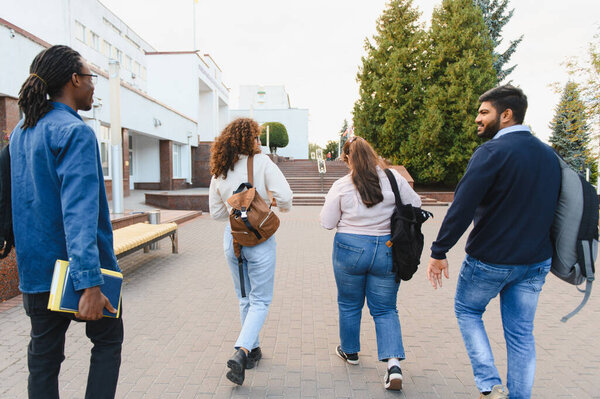 Multi ethnic group of students walking together on a university campus, sharing a moment of education and friendship