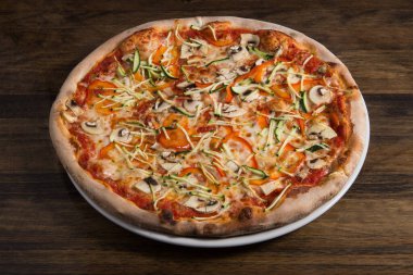 Yukarıdan dereotlu mantarlı pizza ve ahşap bir arka planda domates.