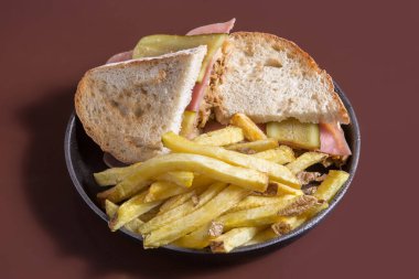 Etli, peynirli, salatalıklı ve patates kızartmalı sıcak sandviç.