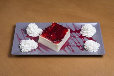 Beyaz tabakta ahududulu peynirli kek.