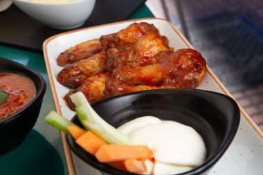 Barbekü tavuk kanadı. Yavaş pişiren tatlı ve baharatlı. Fırında kızartılmış chiken tabakta bbq kırmızı sosuyla..