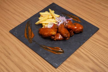 Barbecue chicken wings with bbq sauce on plate on wooden background