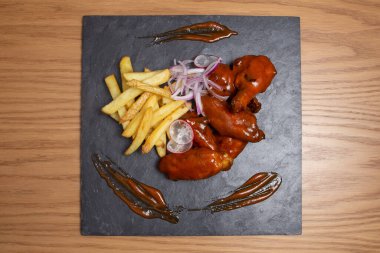 Barbecue chicken wings with bbq sauce on plate on wooden background