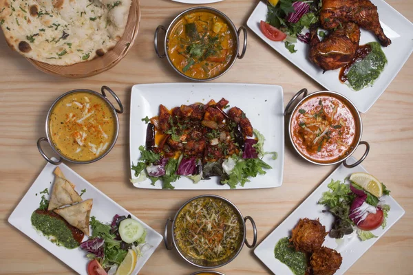 Set of Indian food dishes, with pilau rice, vegetable samosas, red curry