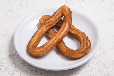 küçük tabak beyaz arka plan üzerinde birkaç churros.