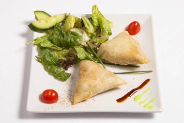 Beyaz tabakta taze salata ile Samosas