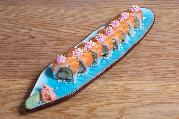 Uramaki suşi rulo somon füme, avokado, krem peynir, chukka ve tobico ile beyaz tabakta. Sushi menüsü. Geleneksel Japon yemekleri.