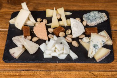 Tasting cheese dish on a black rustic plate.