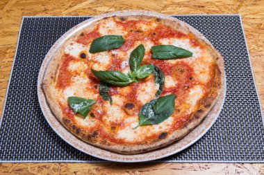 Zeytinyağı, domates, mozzarella ve fesleğenli taze pişmiş pizza..