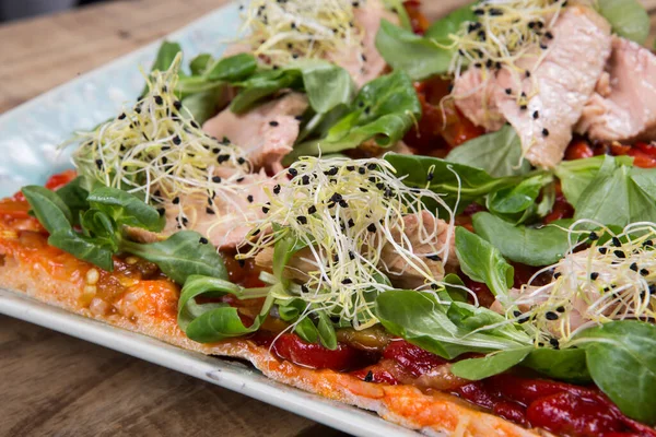 Dikdörtgen pizza ton balığı, soğan, domates ve ahşap masada siyah zeytin.