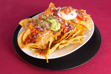 Bir tabak lezzetli tortilla naçosu erimiş peynir sosu, kıyma, biber, kırmızı soğan, yeşil soğan, domates, siyah zeytin, salsa ve soslu ekşi krema..