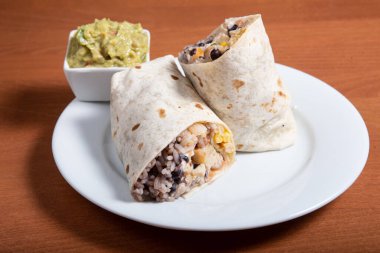 Beyaz tabakta sığır etli, fasulyeli ve domatesli dürüm.