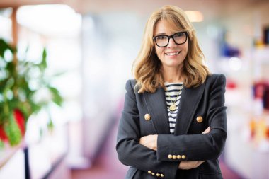 Orta yaşlı çekici bir iş kadınının portresi kollarını fuayede kavuşturmuş duruyor..