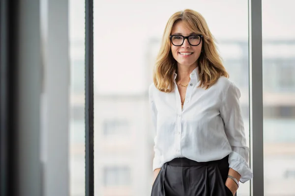 有魅力的中年商业女性 穿着白衬衫 站在办公室时面带微笑 — 图库照片