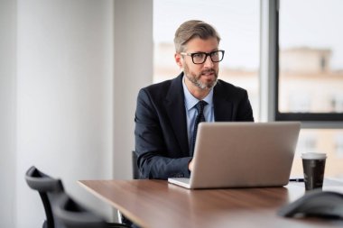 Ofiste çalışırken takım elbise giyen, kravat takan ve dizüstü bilgisayar kullanan yönetici işadamlarının yakın çekimi..