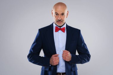 Gri arka planda duran kendine güvenen iş adamının portresi. Gülümseyen profesyonel erkek takım elbiseli ve papyonlu. Boşluğu kopyala. 