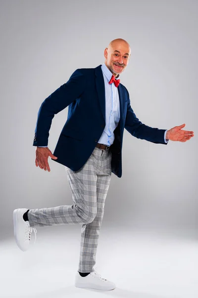 Full length of funny faced man walking against isolated white background. Smiling caucasian man wearing blazer and checked trousers. Copy space.
