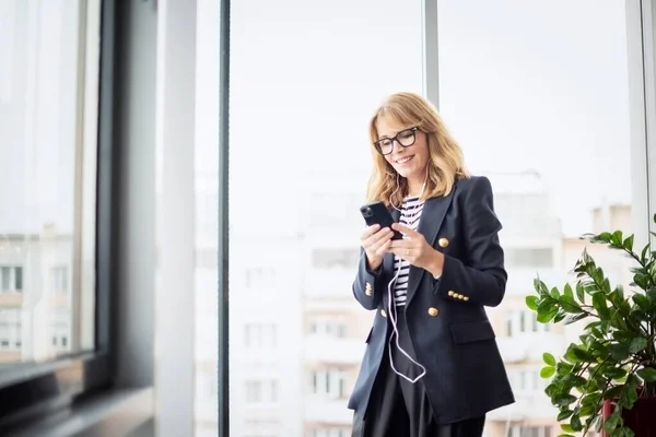 Uma Empresária Meia Idade Sorrindo Usando Smartphones Fones Ouvido Enquanto — Fotografia de Stock