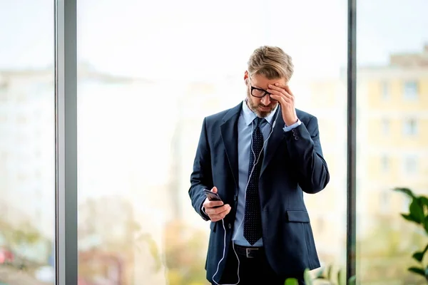 Thoughtful Male Professional Using Smartphone Earphones While Standing Office Professional — Fotografia de Stock