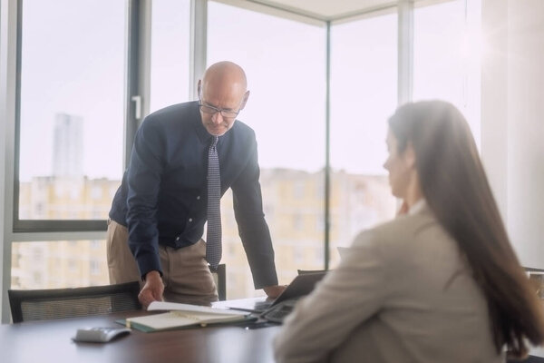 Командная работа в офисе. Бизнесмен, стоящий за рабочим столом и консультирующийся со своим коллегой.