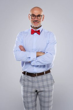 Close-up of mid aged man wearing shirt and bow tie while standing at isolated grey background. Copy space.
